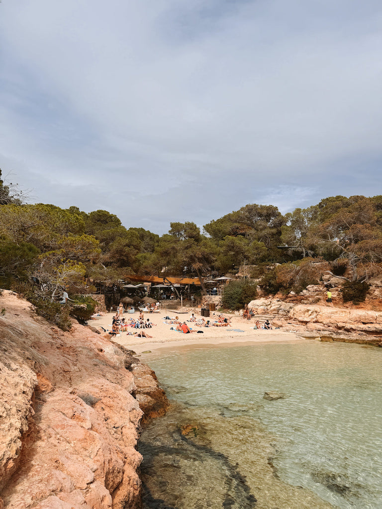 Cala Conta beach  in Ibiza, Spain. Crystal clear waters and people tanning, soaking up the sun. 